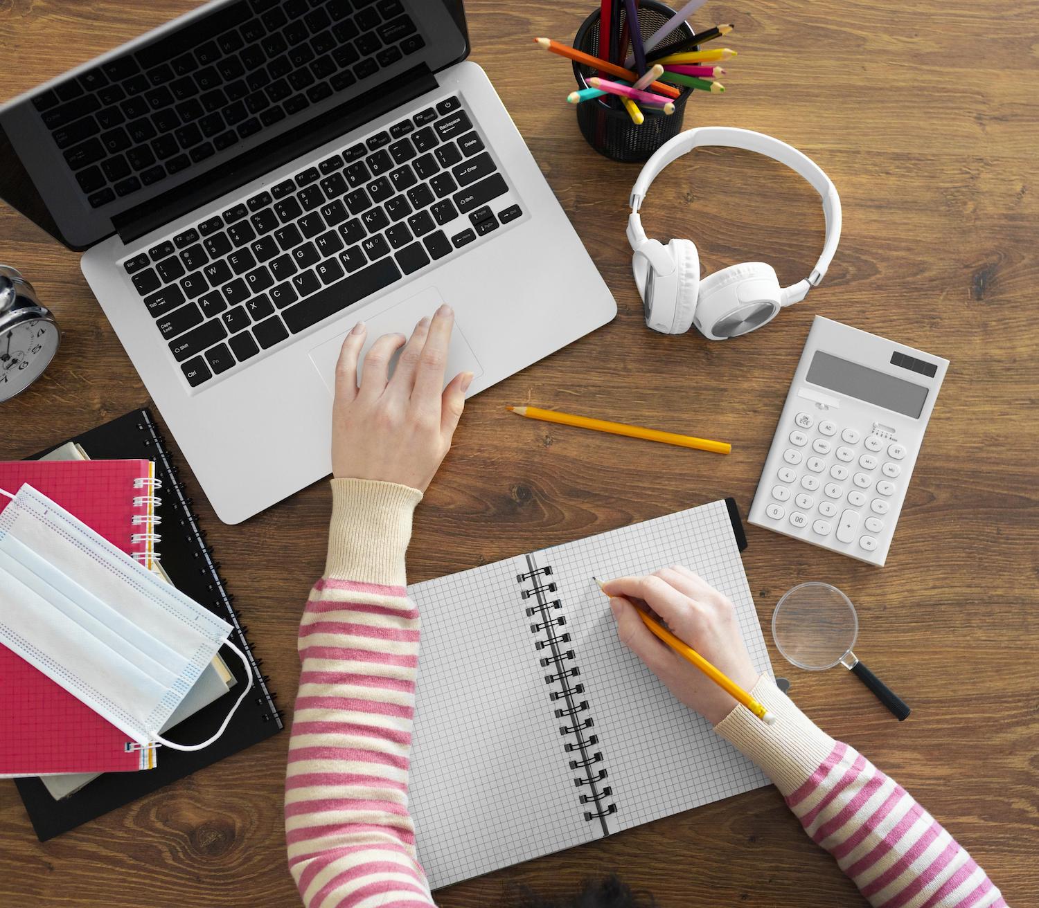 woman leaning against a couch looking at a laptop