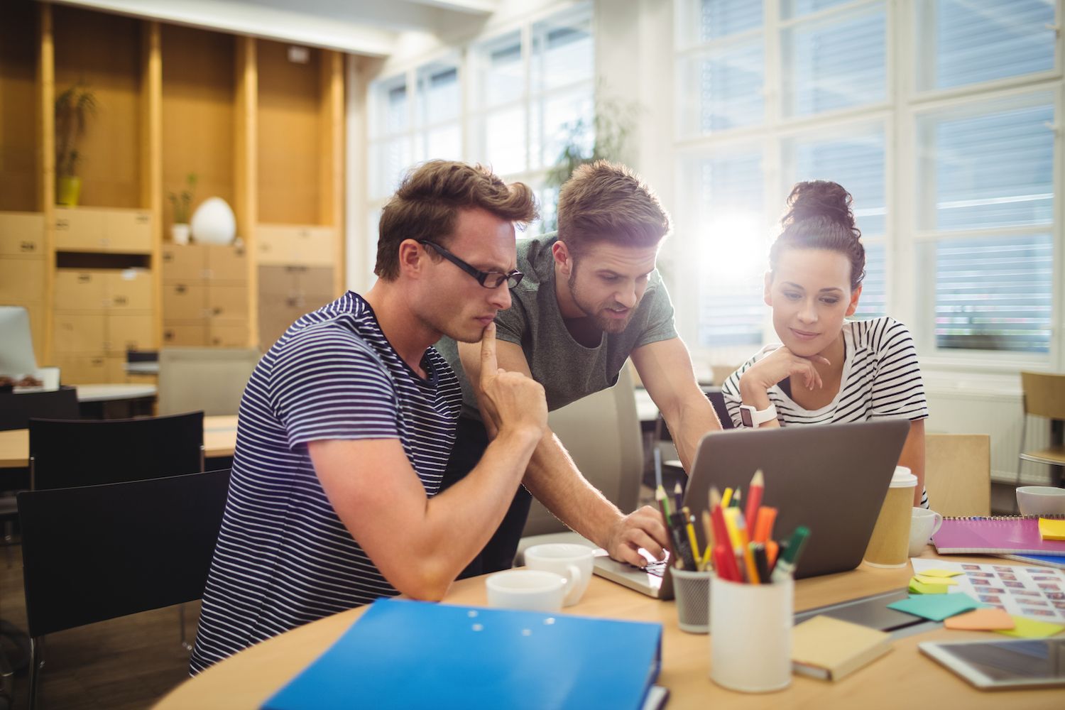 man discussing something with a colleague in front of a laptop